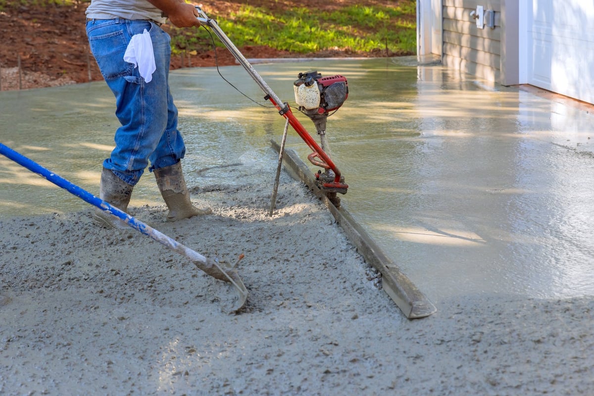 Professional worker using tamping machine to align compacted concrete on new driveways