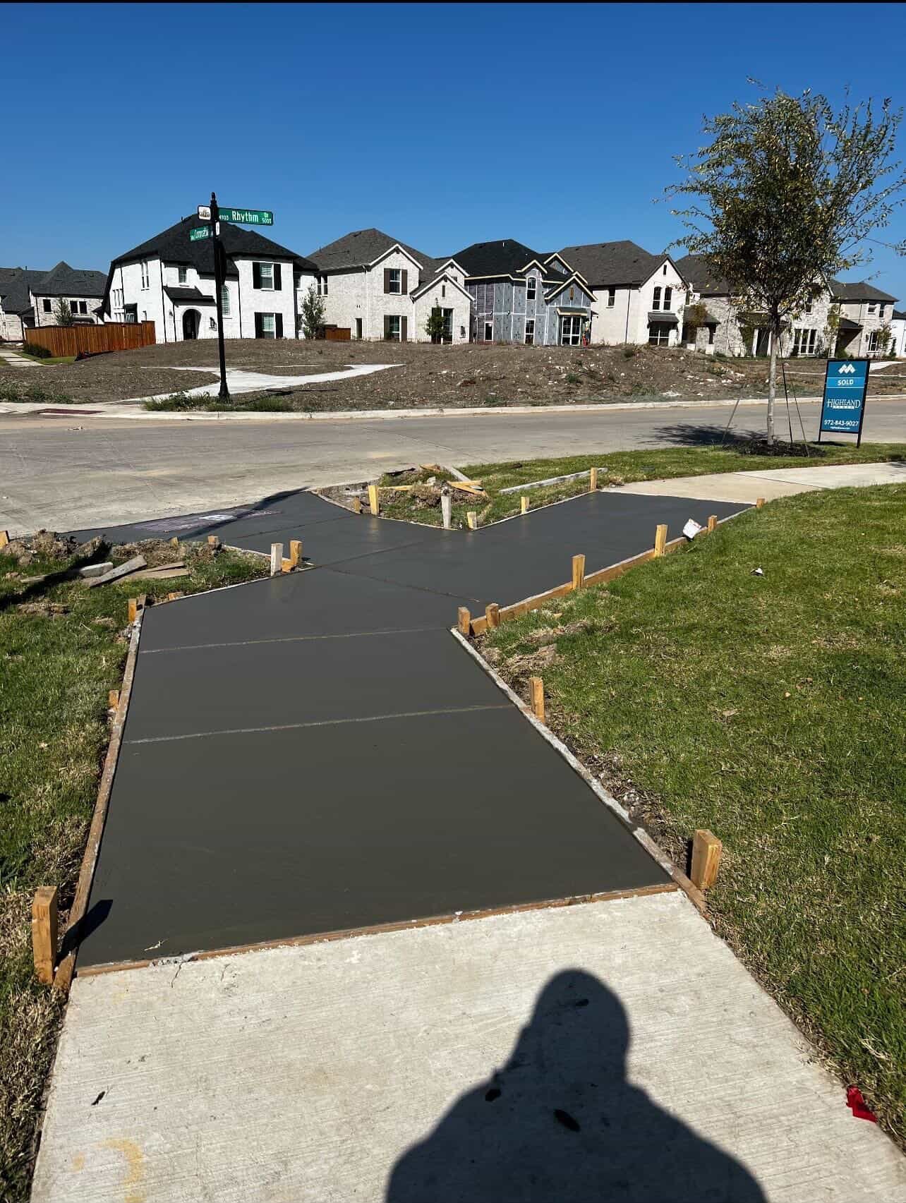 Wet concrete foundation with wooden frame supports in residential neighborhood under construction on sunny day