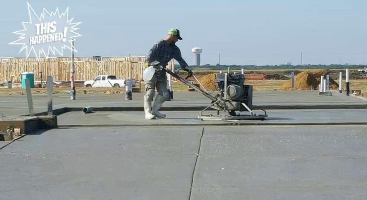 Worker using heat gun to install roofing material on flat roof surface at construction site